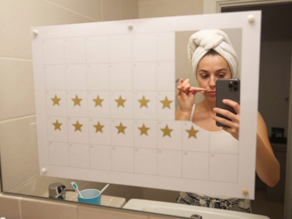 Adult adding a star to her habit chart on the bathroom mirror