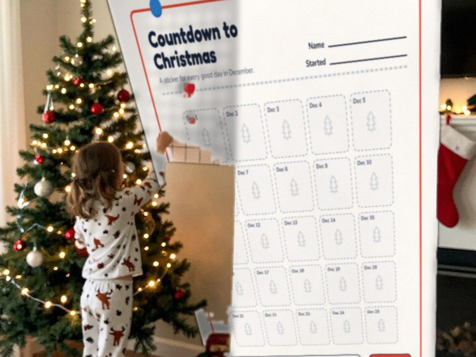 Child adding a sticker to the Christmas countdown behavior chart next to the tree