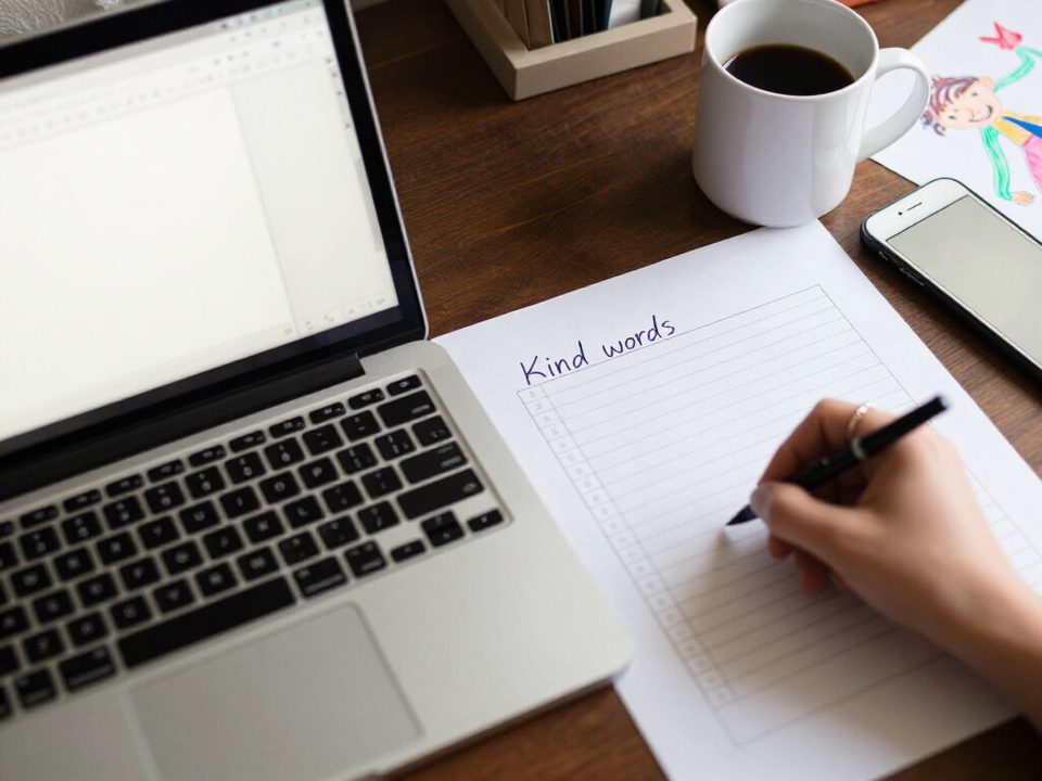 Parent filling in a blank behavior chart template by hand at the desk